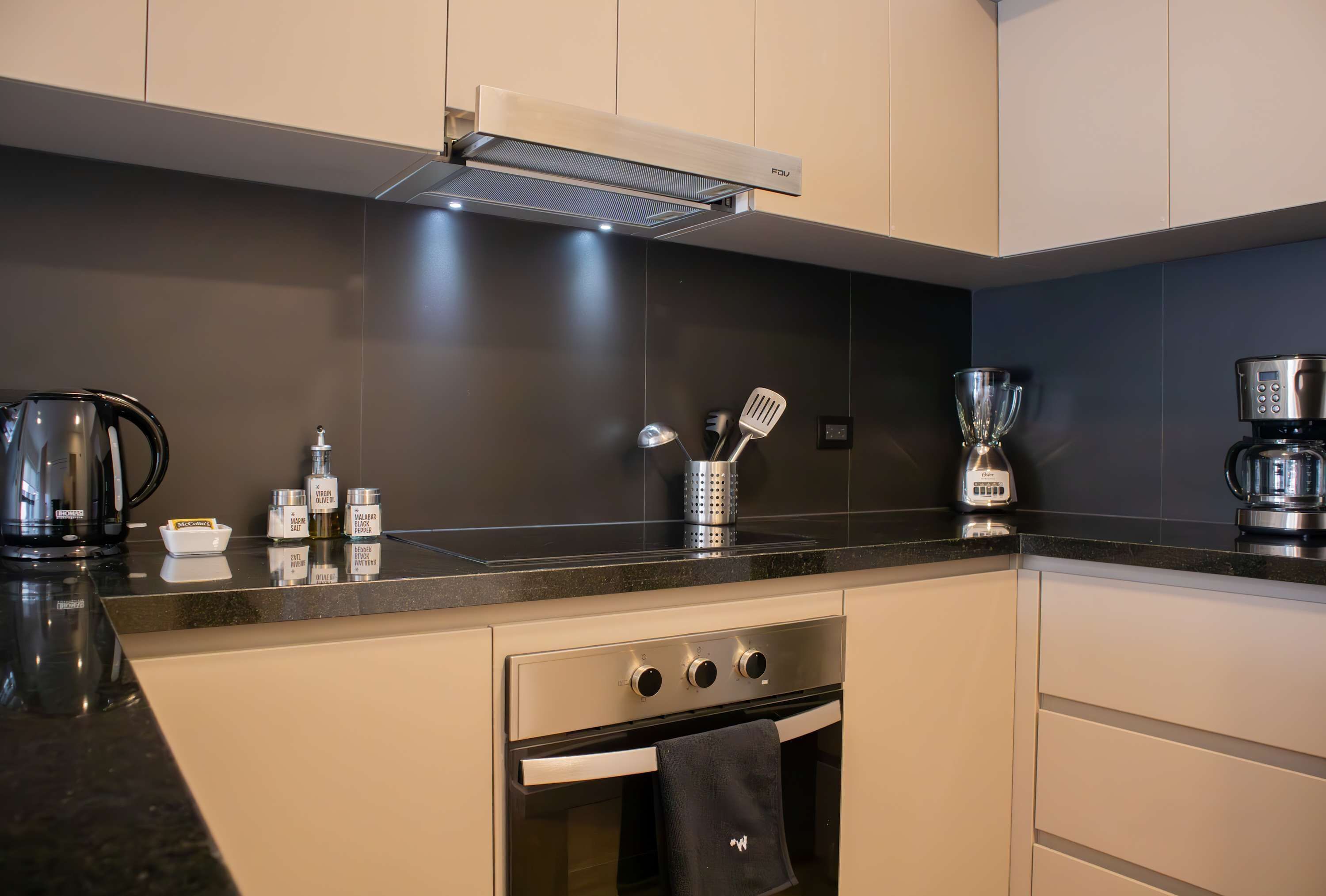 A modern kitchen with a built-in oven, a coffee maker, and various kitchen utensils on the countertop.