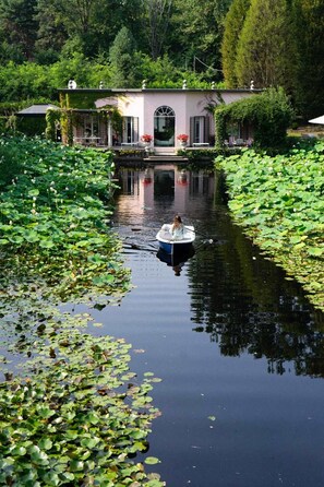A houseboat docked in a calm river surrounded by lush greenery and lily pads. - Tranquil 1BR Villa in Revislate (Veruno)