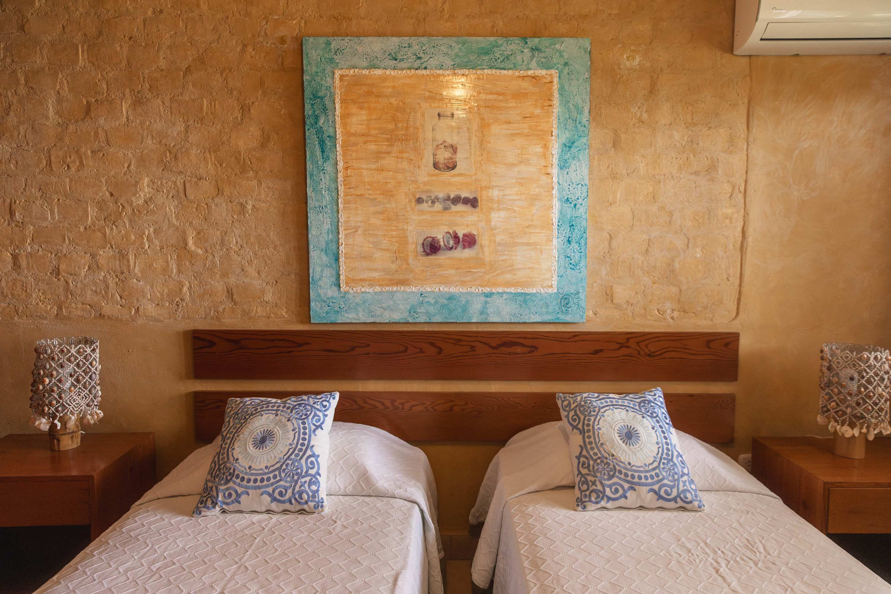 Una camera d'albergo con due letti, una testiera in legno, un elemento decorativo a parete e una parete strutturata.