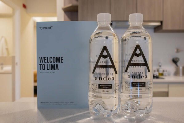 Two bottles of 'Aandea' water with a 'Welcome to Lima' sign in the background.