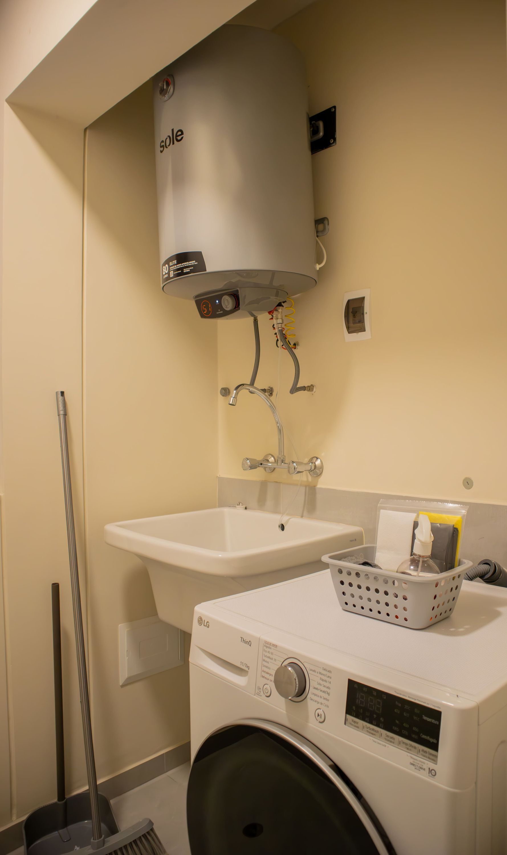 A compact bathroom with a washing machine, a sink, and a toilet.