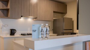 Une cuisine moderne avec des meubles en bois, un plan de travail blanc et un réfrigérateur en acier inoxydable.