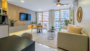 A modern living room with a sofa, dining table, and TV.