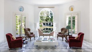 A spacious room with a checkered floor, a central coffee table, and four armchairs. - Charming 1BR Suite in Revislate (Veruno)