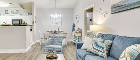 A modern living room with a blue sofa, a wooden coffee table, and a patterned armchair.
