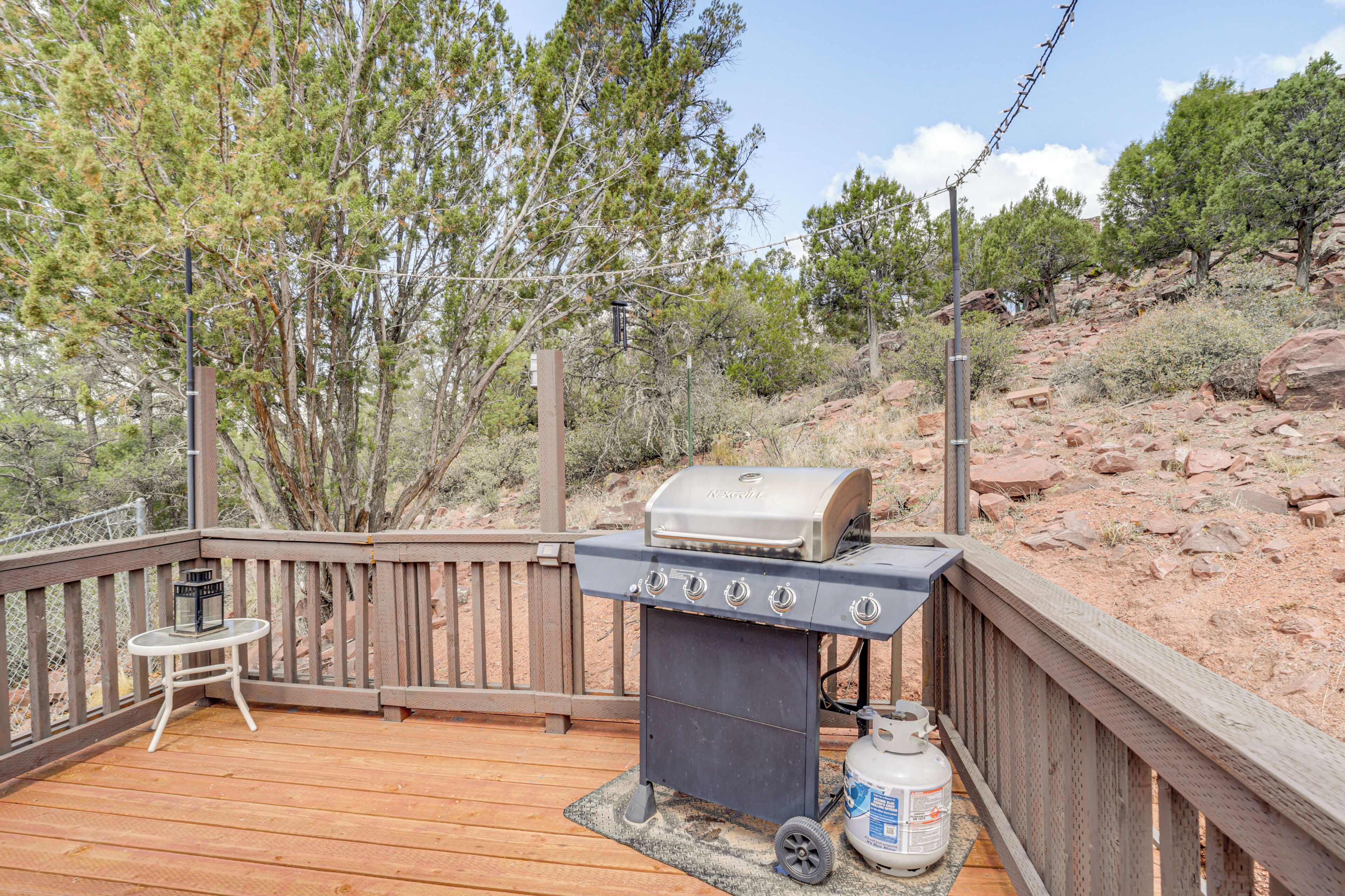 A wooden deck with a barbecue grill and a propane tank.