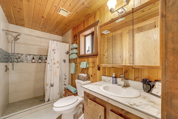 A wooden cabin bathroom with a shower, toilet, and two sinks.