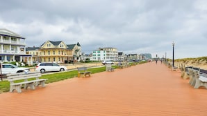 Ein Promenadendeck mit Bänken, einer Rasenfläche und Gebäuden im Hintergrund.