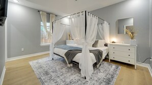 Ein Schlafzimmer mit einem Himmelbett, einem Nachttisch mit Lampe, einem Beistelltisch und einem Spiegel an der Wand.