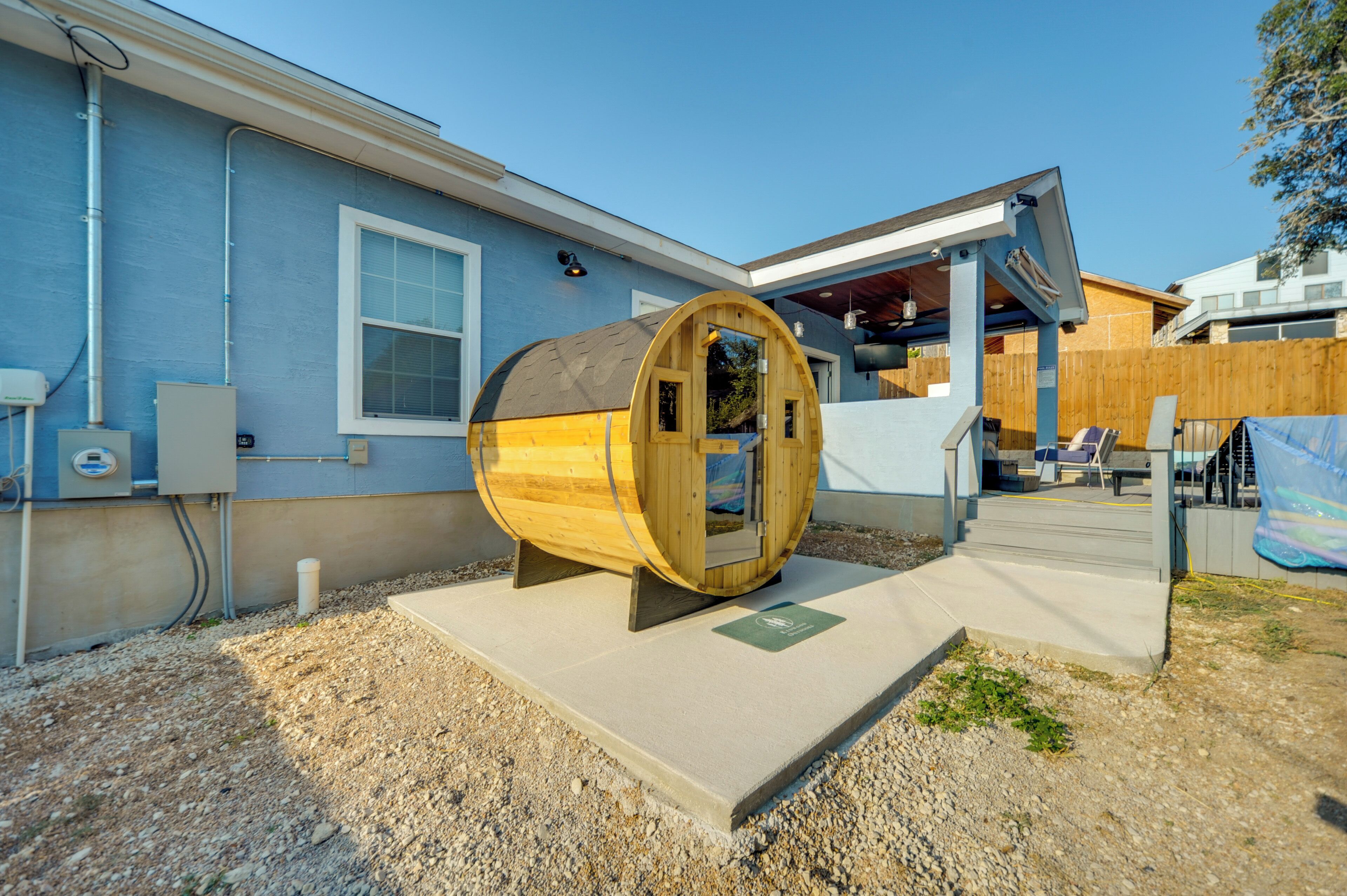 A barrel-shaped structure in front of a building with a window and a covered outdoor area.