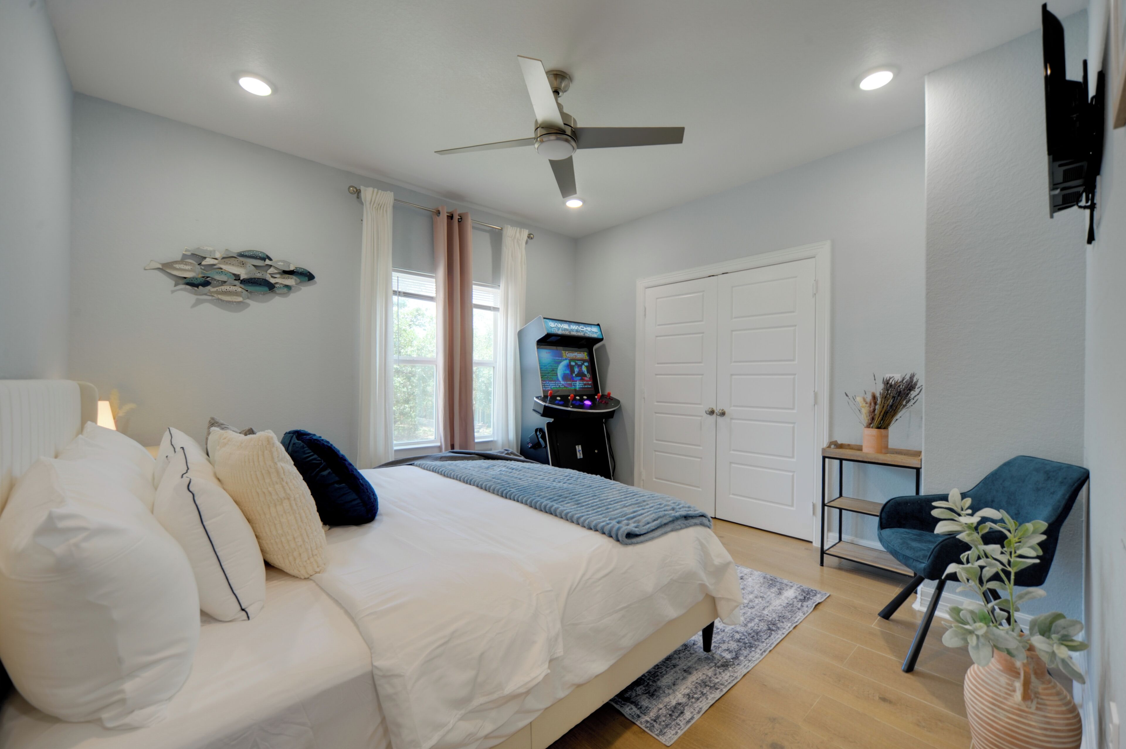 A bedroom with a bed, ceiling fan, and a TV stand with a flat-screen TV.