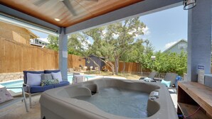 Ein Whirlpoolbereich mit Holzterrasse, Schwimmbad und überdachter Sitzgruppe.