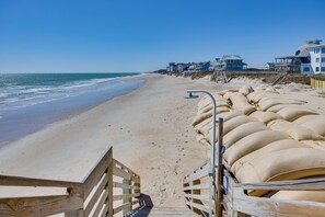 A beach with a wooden walkway leading to a sandy area. There are houses in the background. - Walk to Ocean: North Topsail Beach Gem w/ Balcony! (Sneads Ferry)