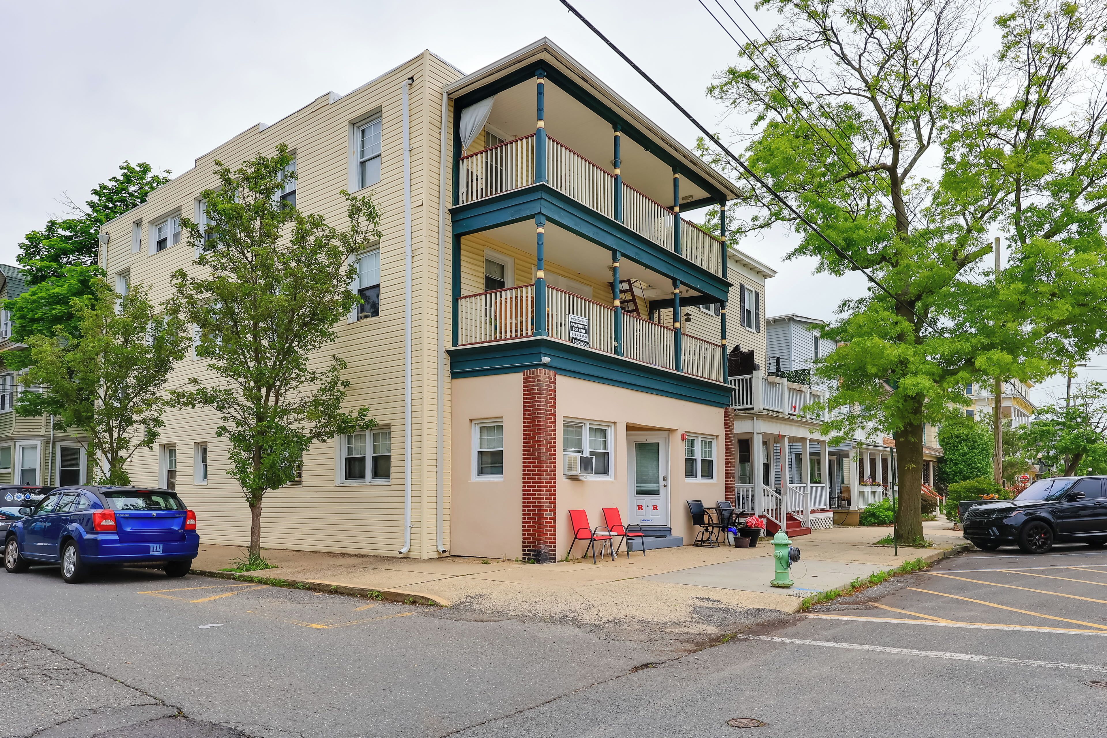 A two-story building with a balcony, a fire hydrant, and a parking lot.