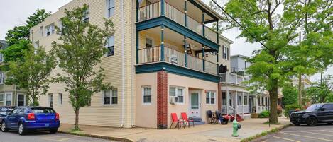 A two-story building with a balcony, a fire hydrant, and a parking lot.