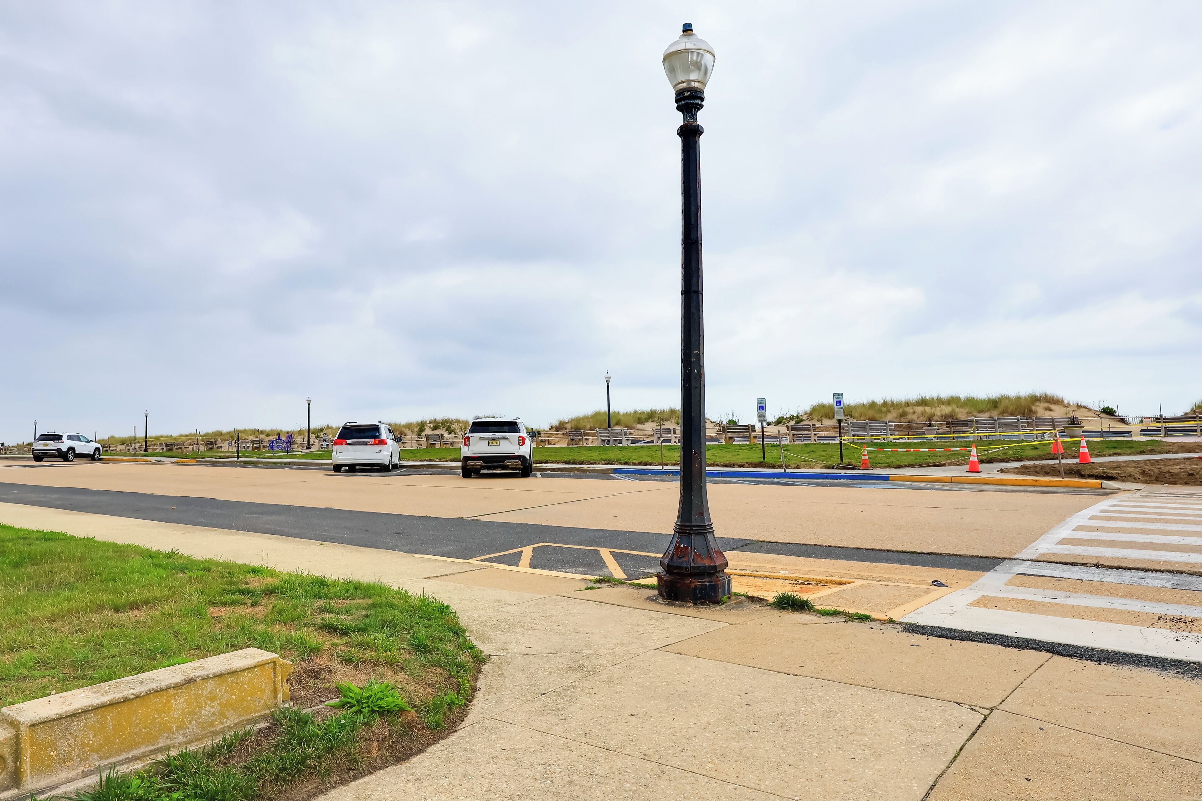 A street with a lamppost, a crosswalk, and cars on the road.