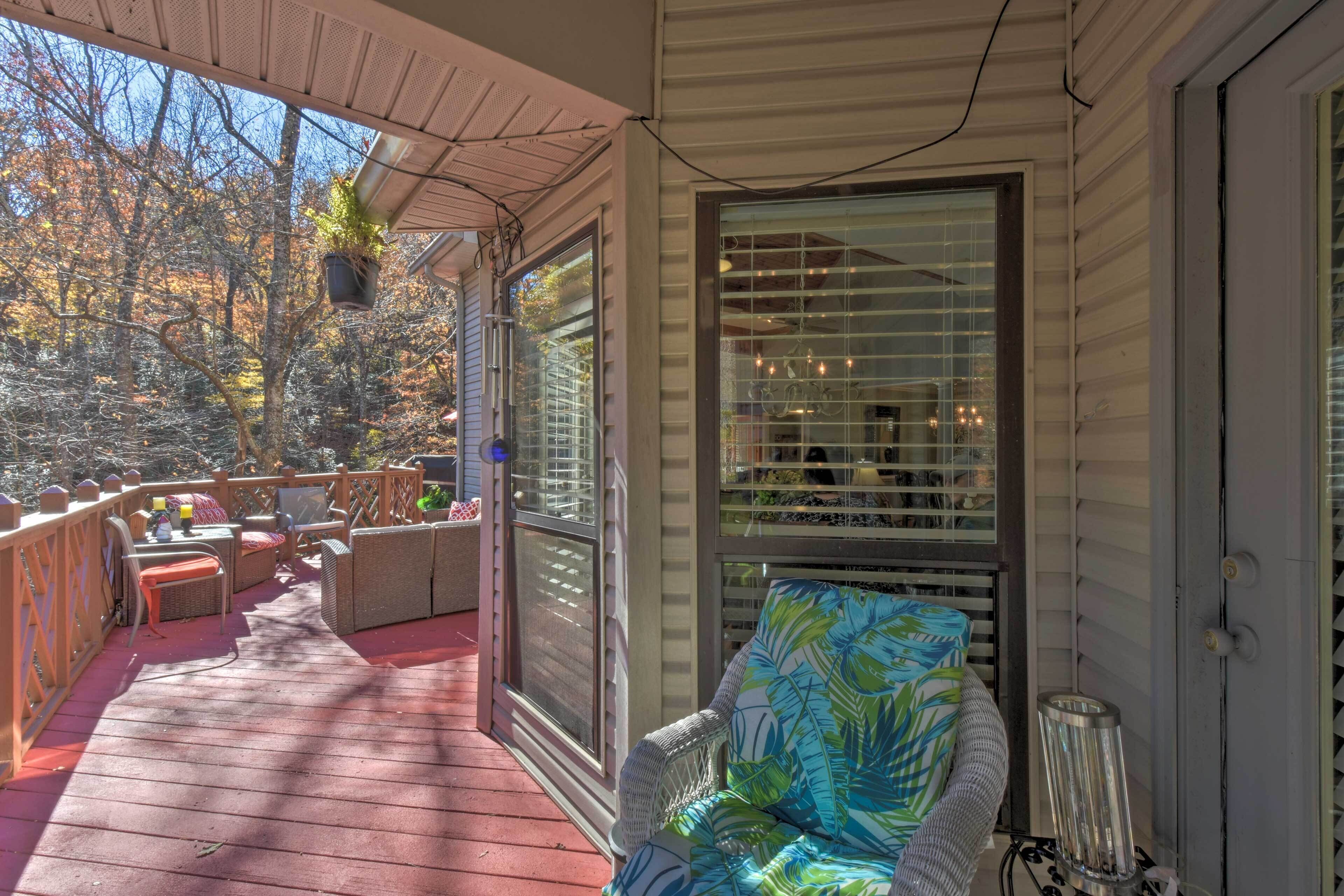 A covered porch with outdoor furniture, a potted plant, and a view of trees.