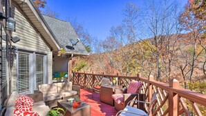Une terrasse extérieure couverte, aménagée avec des meubles en osier, un plancher rouge et une rambarde en bois.