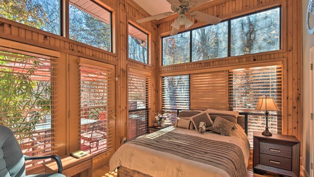 Une chambre à coucher avec un grand lit, des murs en bois et de nombreuses fenêtres.