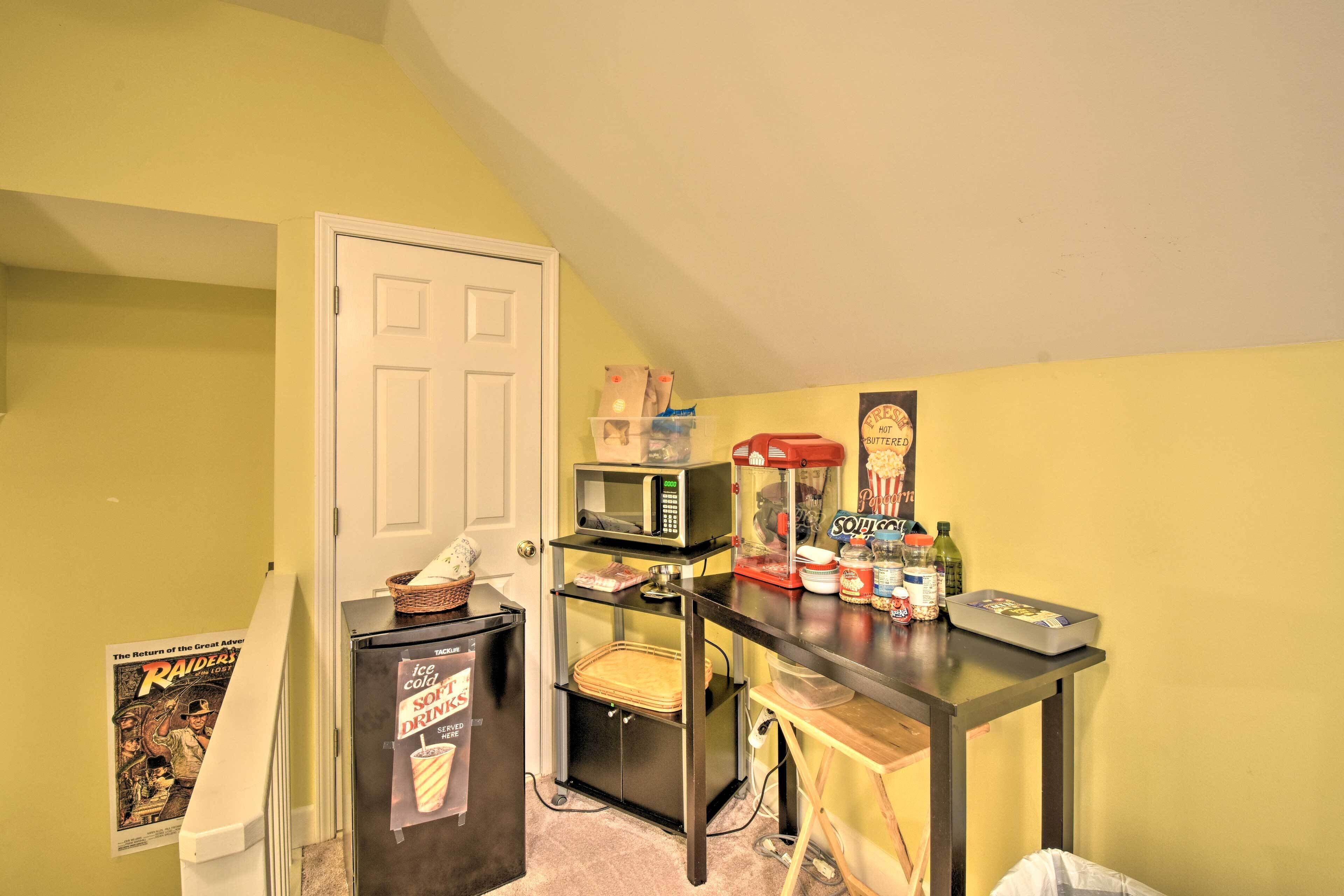 Cocina compacta equipada con microondas, refrigerador y una pequeña mesa con aperitivos y bebidas.
