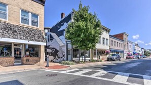 A street view with a building featuring a mural, a tree, and parked cars. - Central Front Royal Getaway on Main Street! (Front Royal)