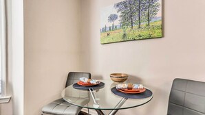 A dining area with a glass table, two chairs, a bowl, and a painting on the wall. - Central Front Royal Getaway on Main Street! (Front Royal)