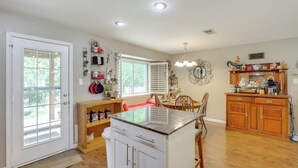 A spacious kitchen with a central island, wooden cabinets, and a dining area with chairs. - 5 Mi to Lewisville Lake: Couple's Retreat w/ Yard (Lewisville)