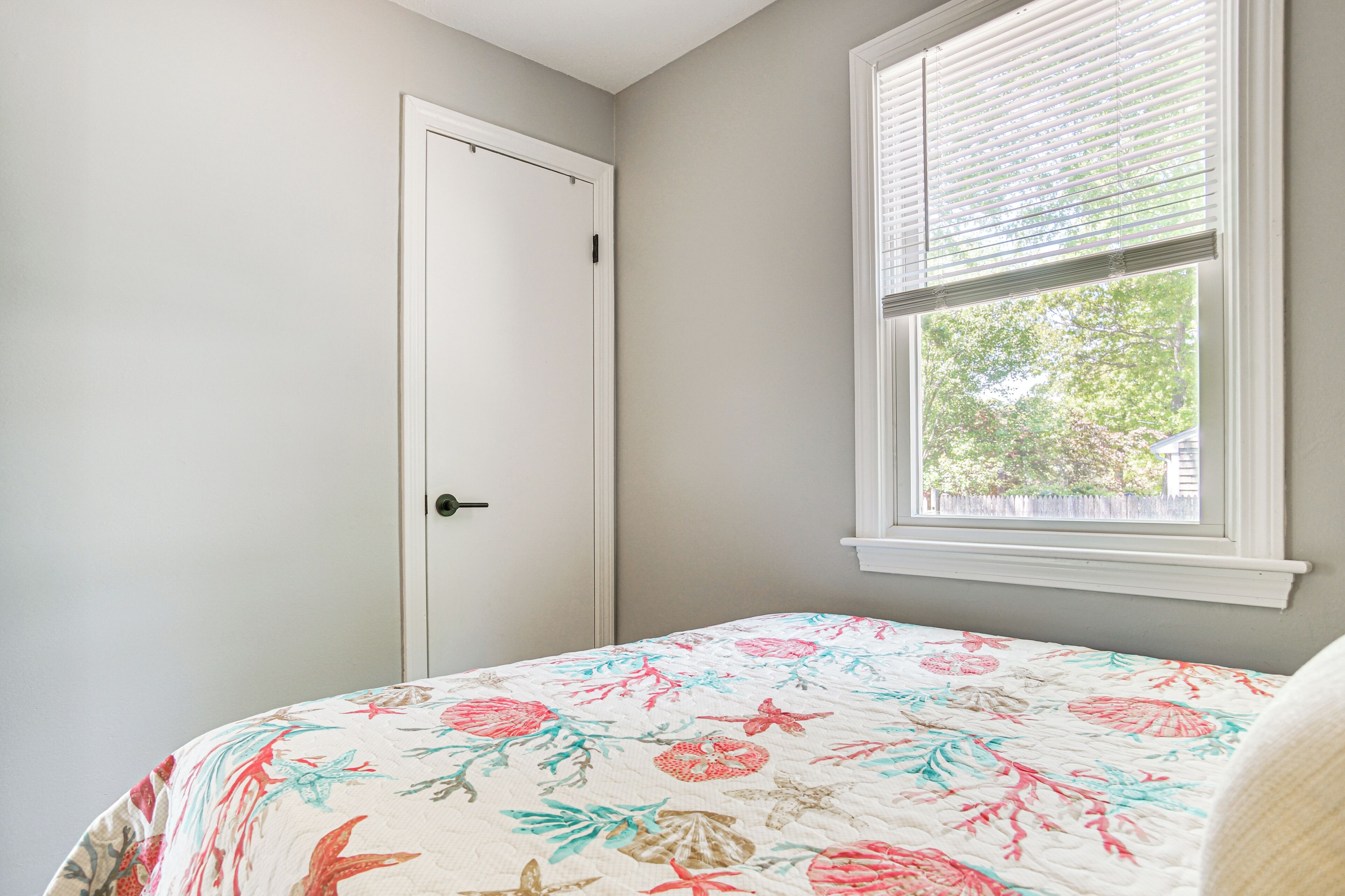 Un dormitorio con cama, puerta y ventana con persianas.