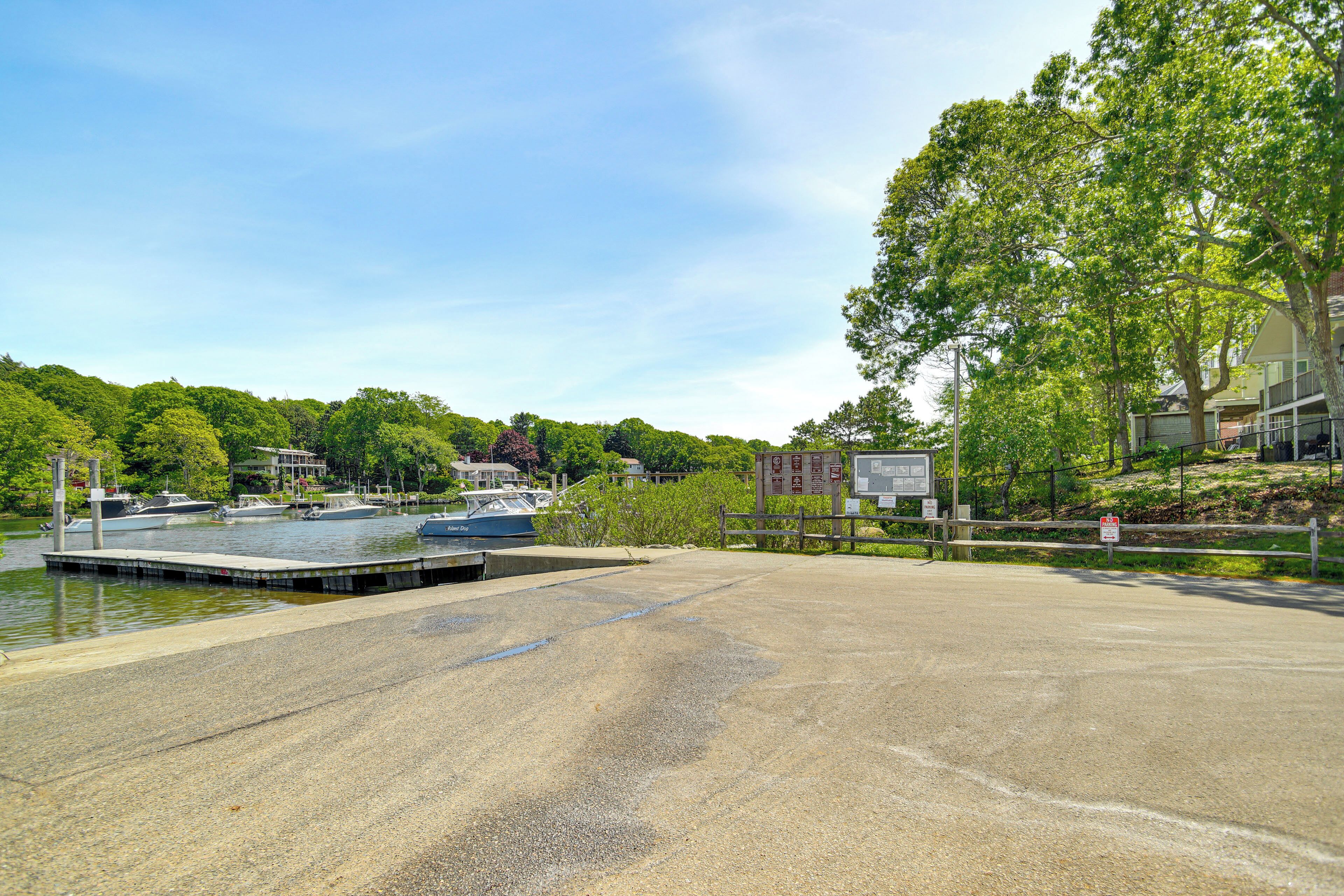 A marina with boats docked, a concrete dock, and a grassy area with trees.