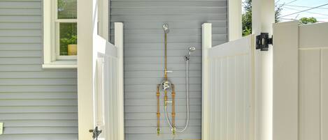 A covered outdoor shower area with a window, a hose, and a faucet.