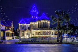 Una casa de estilo victoriano con un porche, una pequeña torre y una valla de piquetes.