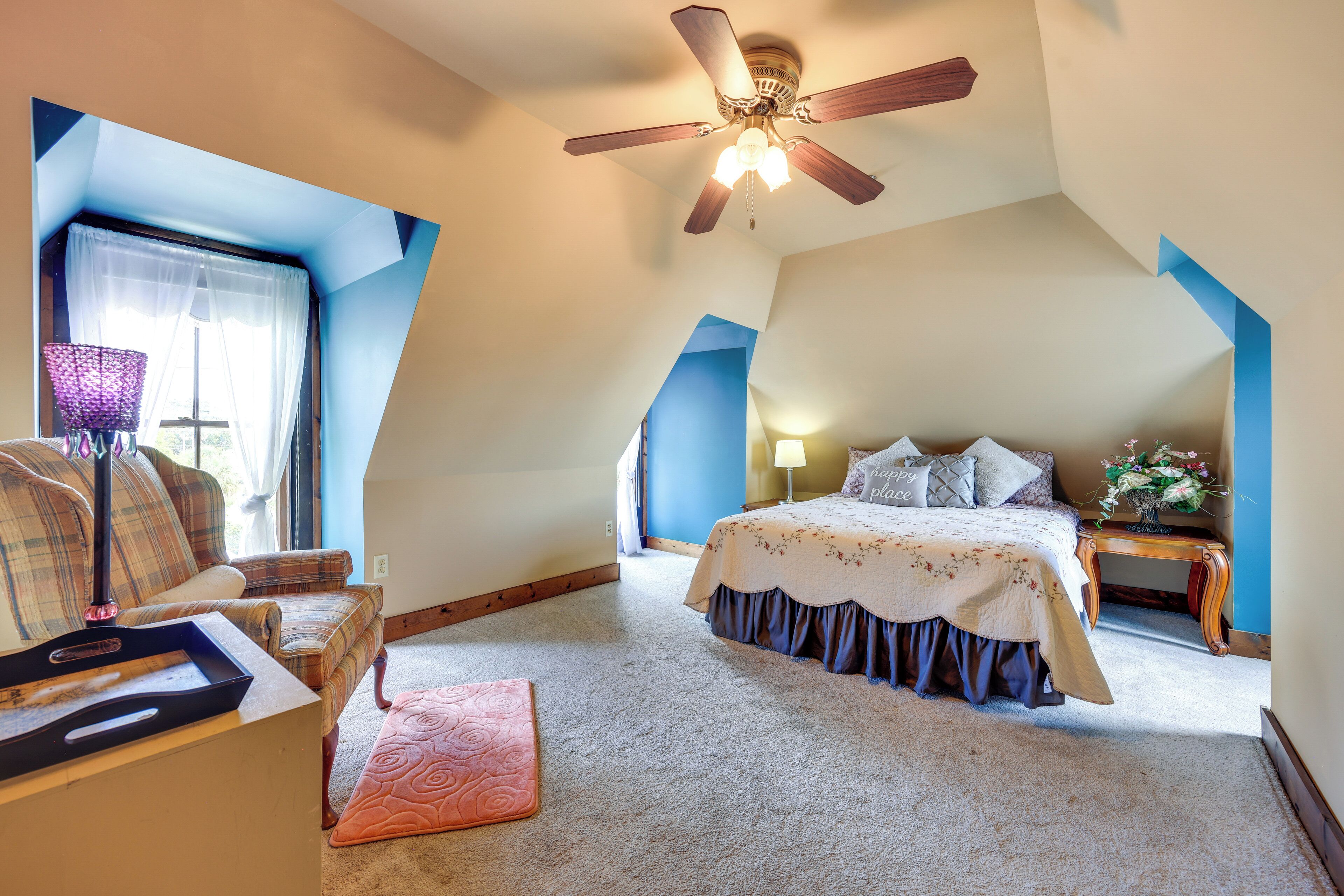 A bedroom with a bed, a chair, a desk, and a ceiling fan.