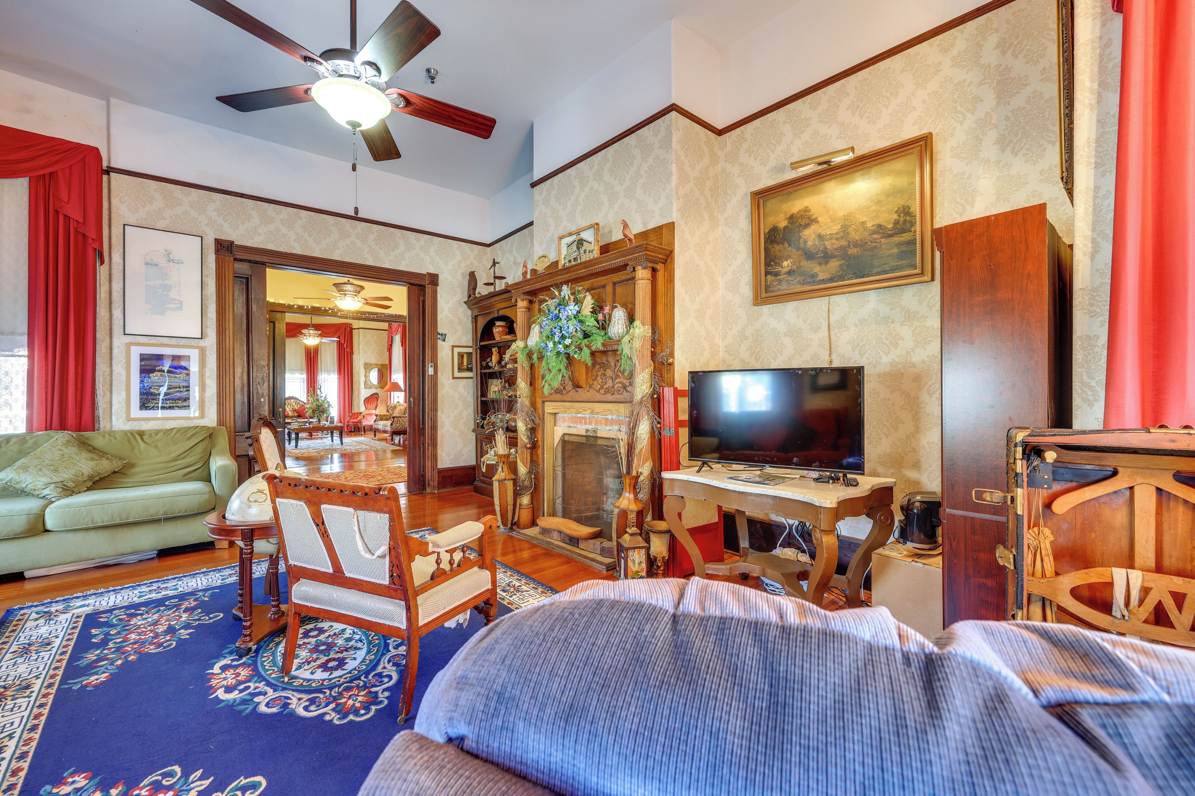 A living room with a green sofa, wooden furniture, a fireplace, a television, and a ceiling fan.