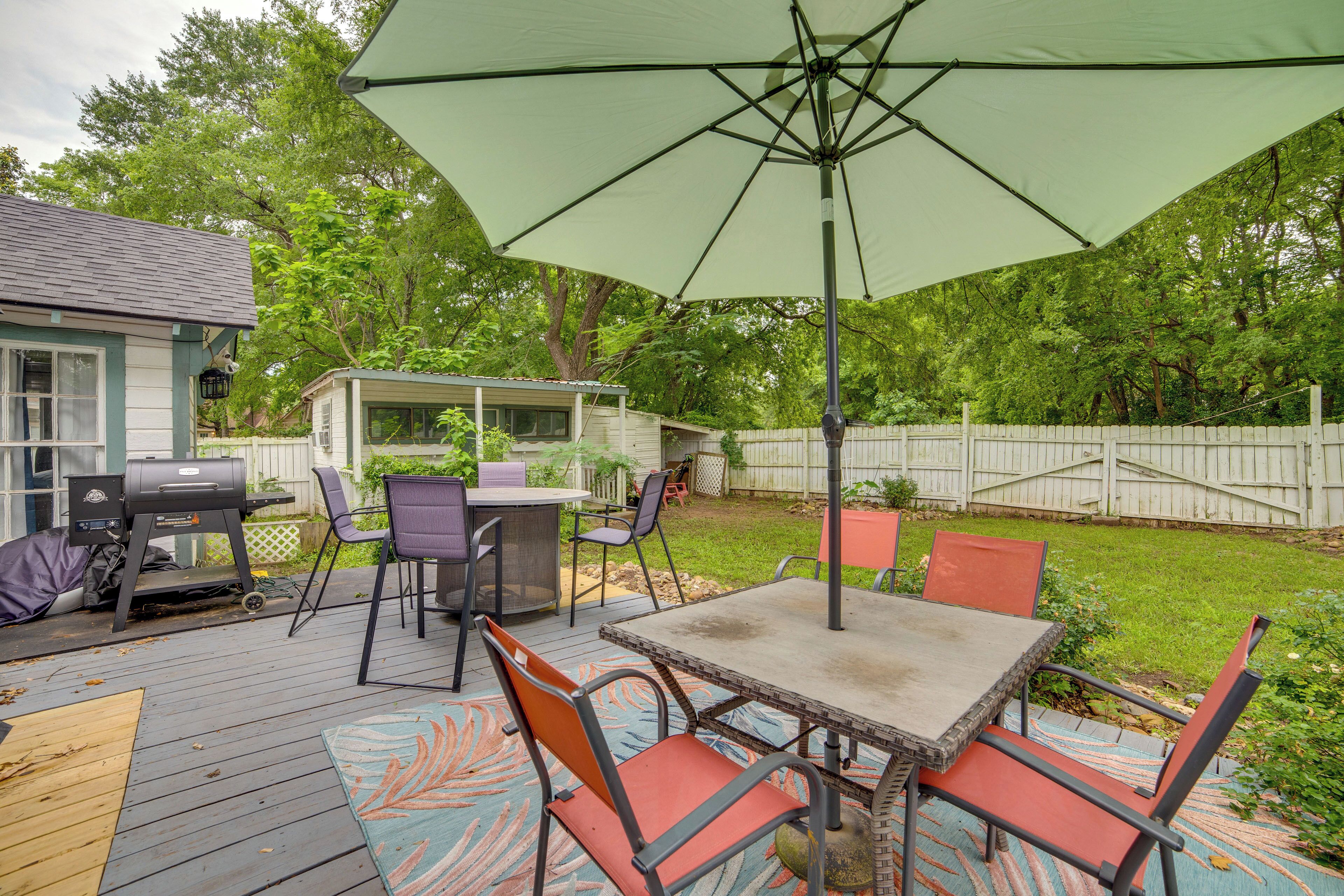 An outdoor patio with a table and chairs, a grill, and a covered area with an umbrella.