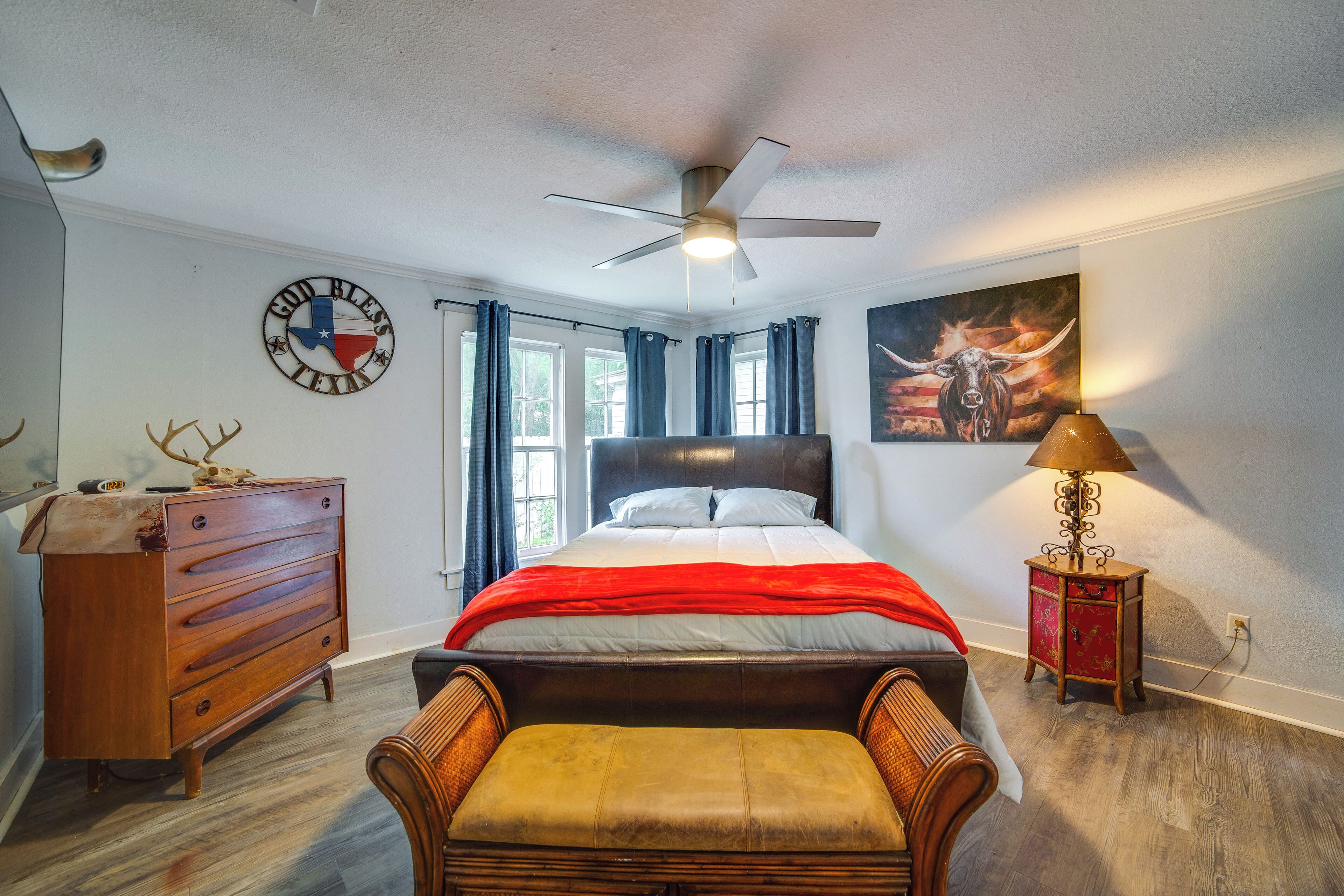 A bedroom with a bed, dresser, chair, and artwork.