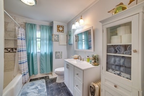 A bathroom with a bathtub, toilet, and vanity with a mirror and shelves. - 7 Mi to Lake Fork: Cottage w/ Deck in Quitman (Quitman)