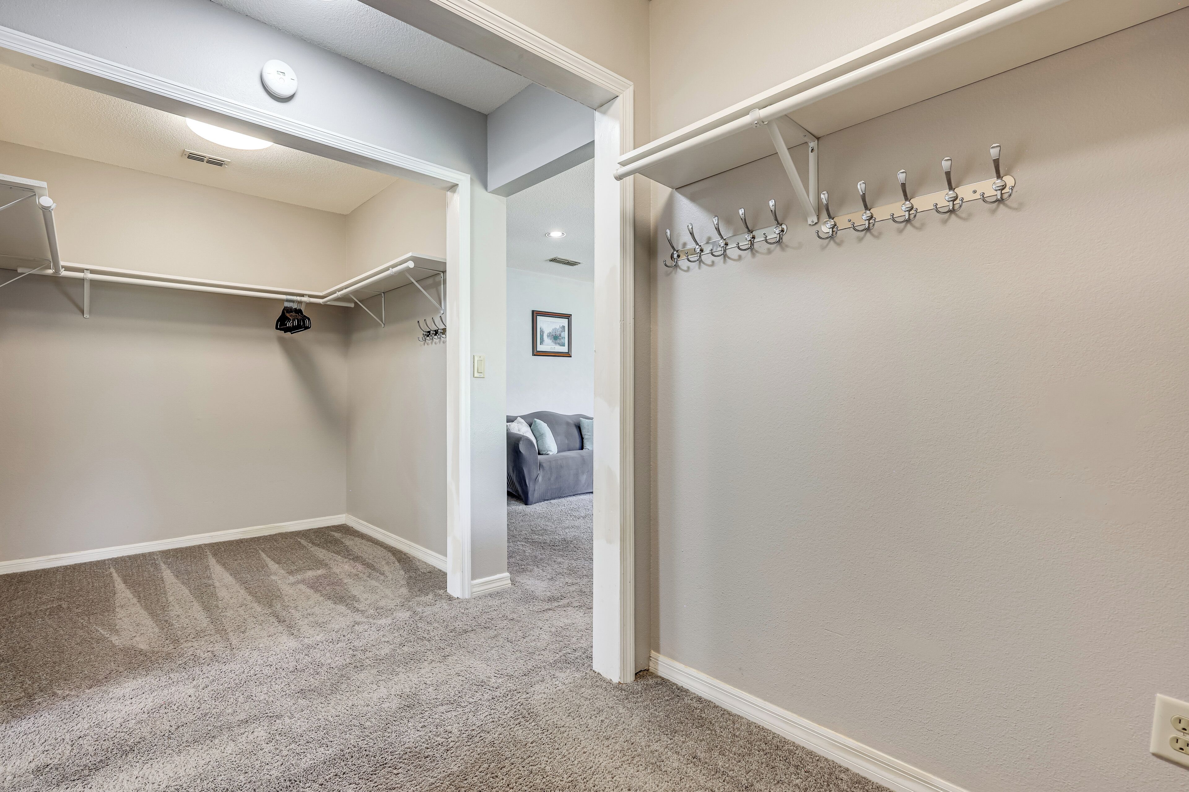 A walk-in closet with a hanging rod and a coat rack.