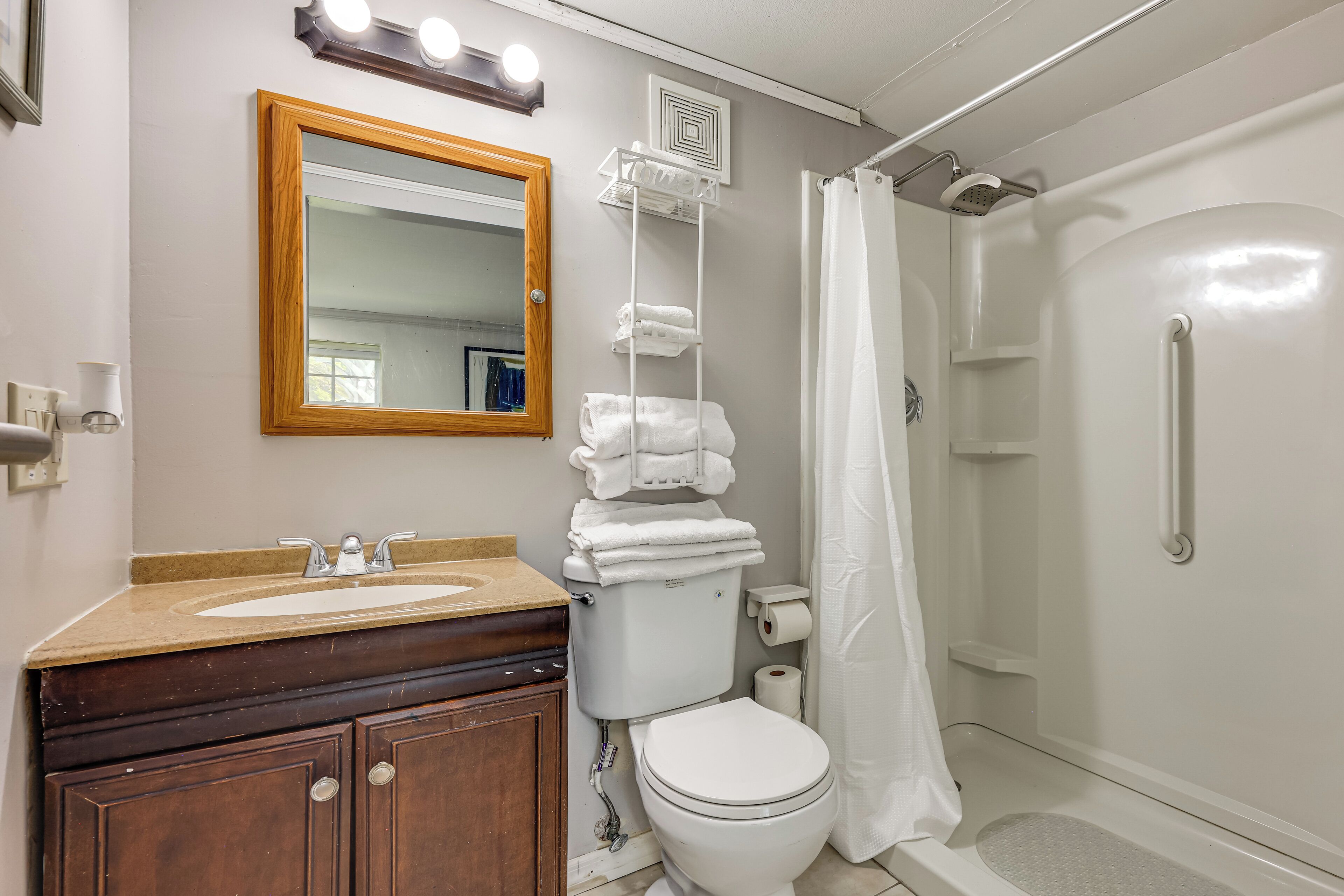 Een badkamer met een wastafel, spiegel, toilet en douche.