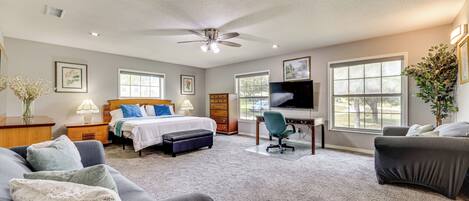 A bedroom with a bed, a desk, a chair, a sofa, and a TV.