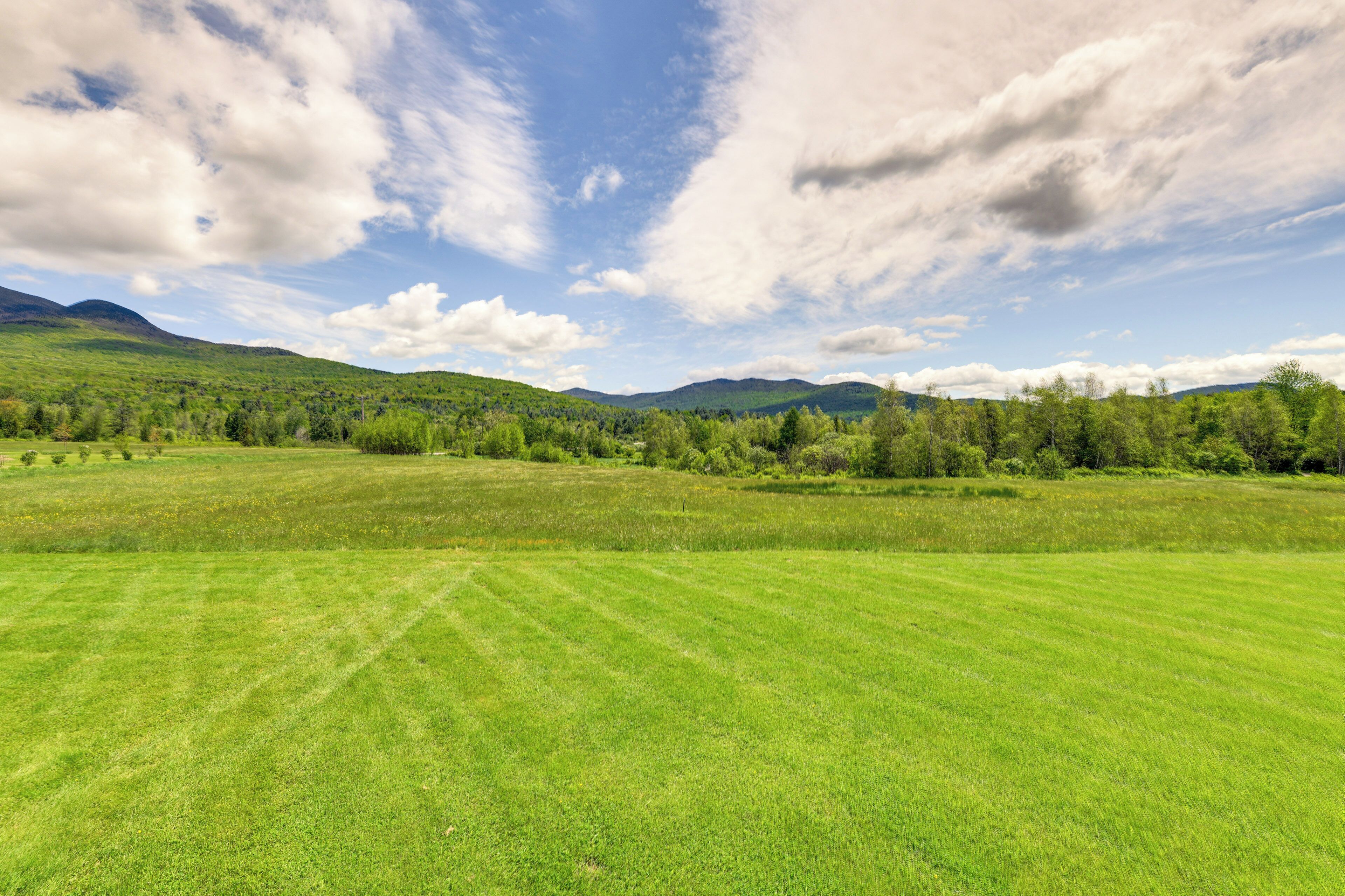 A wide, open field with a distant mountain range under a partly cloudy sky.