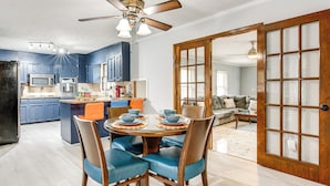 Une cuisine moderne avec des meubles bleus, un four à micro-ondes et un coin repas comprenant des chaises bleues et une table ronde.