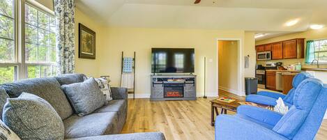 A living room with a gray sofa, blue armchair, wooden flooring, and a ceiling fan.