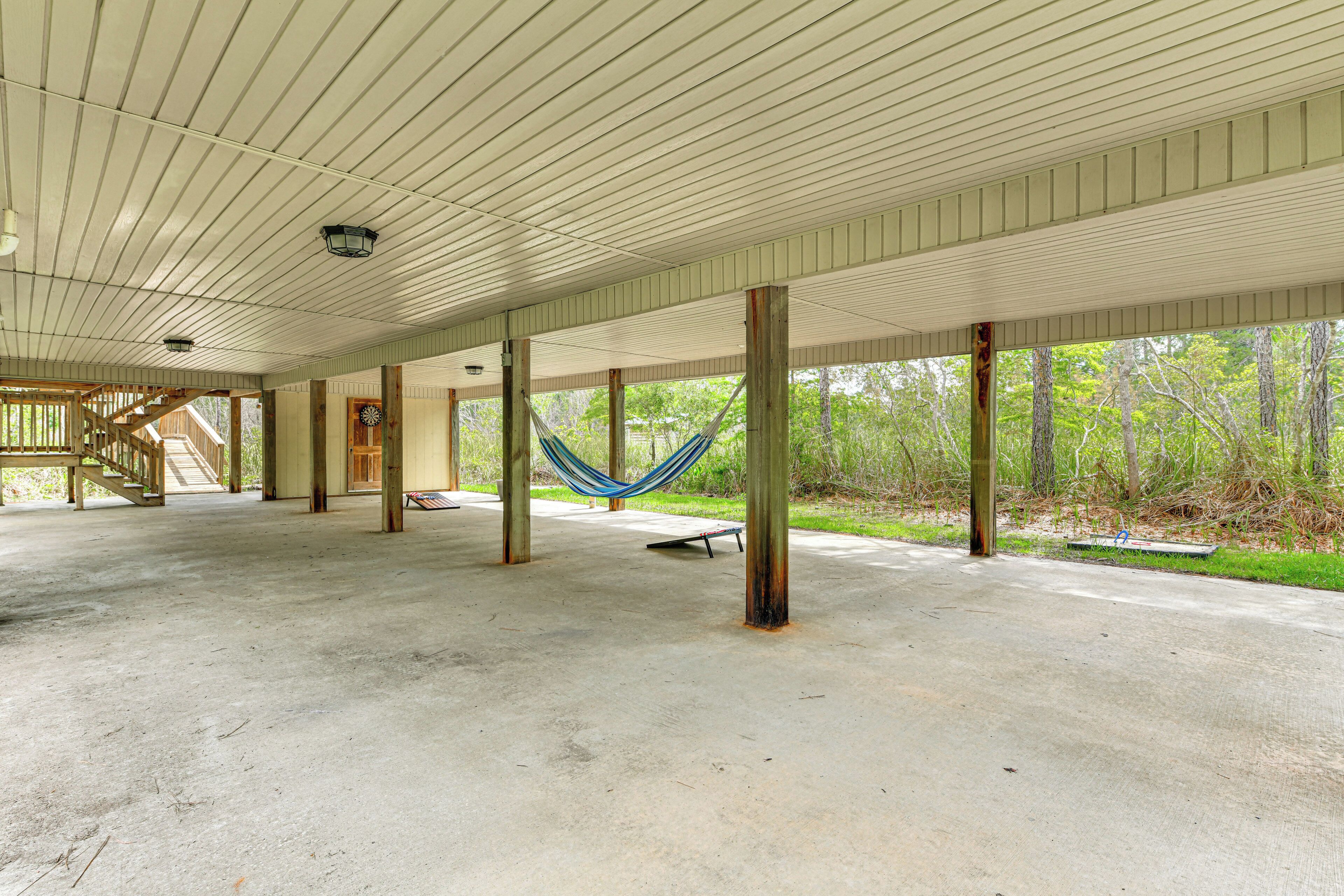 An open covered area with concrete flooring, wooden beams, and a hammock.