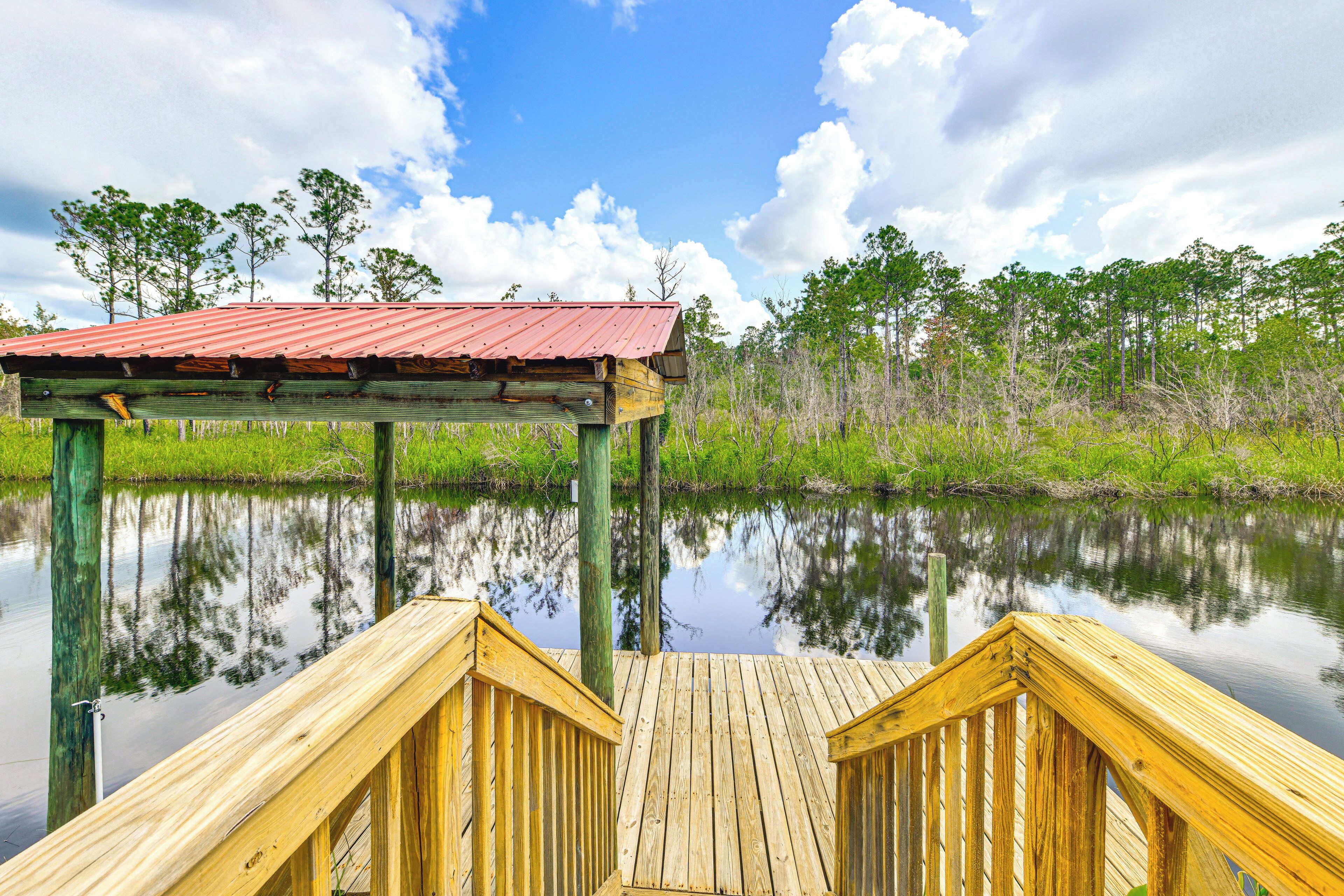 A wooden dock extending into a calm body of water with a red-roofed structure at the end.