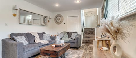A living room with a gray sofa, a wooden coffee table, and a vase with pampas grass.