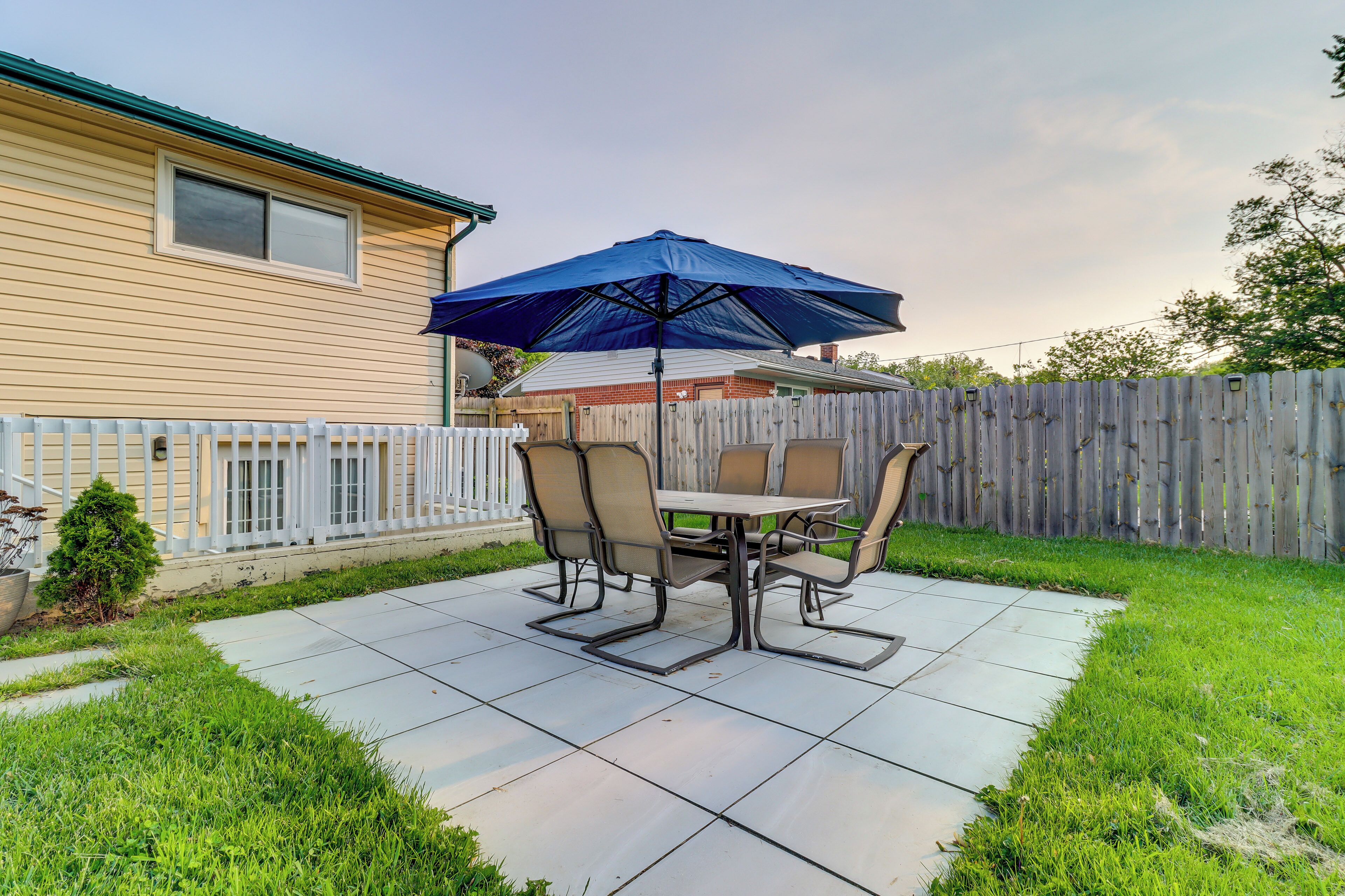A patio with a table and chairs, an umbrella, and a wooden fence.
