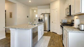 A modern kitchen with white cabinetry, a stainless steel refrigerator, a built-in oven, and a granite countertop. - 3 Mi to Dtwn Kyle: Wfh-friendly Home w/ Patio (Kyle)