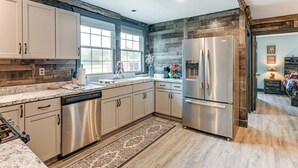 A modern kitchen with stainless steel appliances, wooden accents, and a large window providing natural light. - 5-acre Kingston Getaway: Sauna & Fire Pit (Kingston)