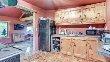 A kitchen with wooden cabinets, a refrigerator, a microwave, and a toaster.