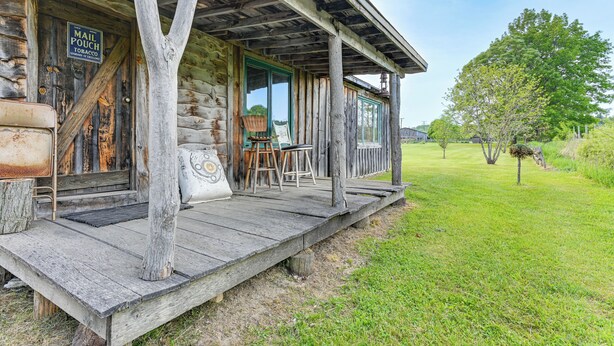 A rustic log cabin with a porch, a mail pouch sign, and a painting setup. - 5-acre Kingston Getaway: Sauna & Fire Pit (Kingston)